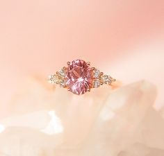 a pink diamond ring sitting on top of a white rock