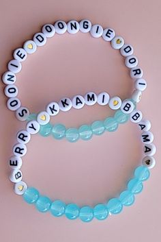 two beaded bracelets with words on them sitting next to each other in front of a pink background