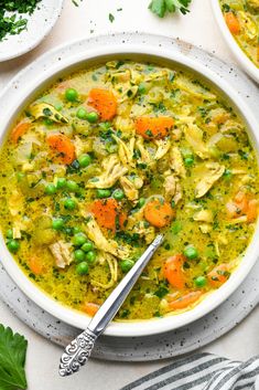 two bowls of chicken noodle soup with carrots and parsley on the side