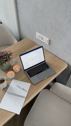 a laptop computer sitting on top of a wooden desk next to a cup of coffee