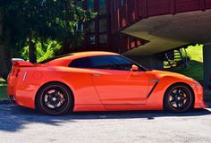 an orange sports car parked in front of a building