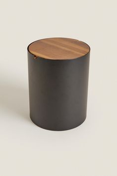 a round black container with a wooden lid