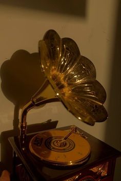 an old record player with a golden horn on it's head and the shadow of a human hand