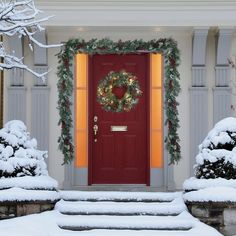 a red door is decorated with christmas wreaths