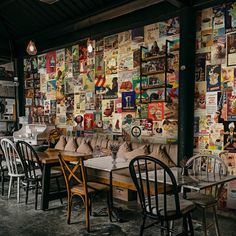 a restaurant with tables and chairs in front of a wall full of posters on the walls