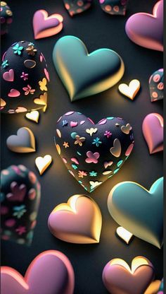 many heart shaped objects are scattered on a black surface with pink, blue and yellow hearts