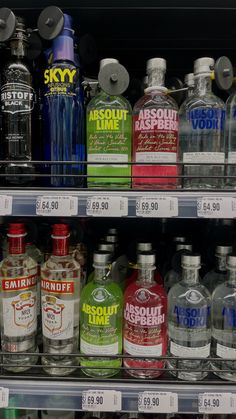 bottles of vodka are on display in a grocery store shelf with price tags for each bottle