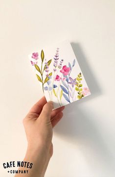 someone holding up a card with watercolor flowers on it