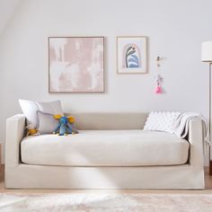 a living room with a white couch and two pictures on the wall above it,