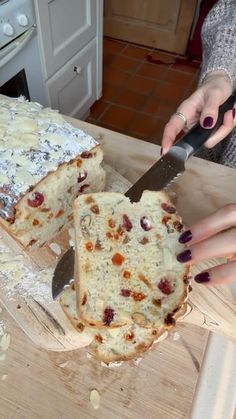 a woman cutting a cake with a knife on a wooden table in front of her