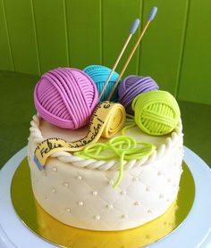 there is a cake decorated with yarn and crochet hooks