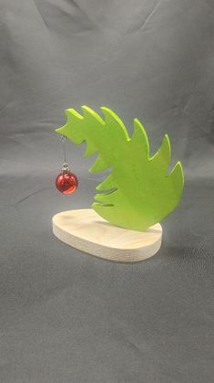 an ornament with a green leaf and a red bauble hanging from it