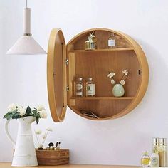 a wooden shelf with bottles and vases on it in front of a white wall