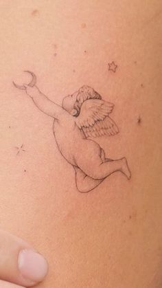 a small tattoo on the back of a woman's stomach with an angel flying above it