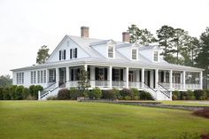 a large white house sitting on top of a lush green field