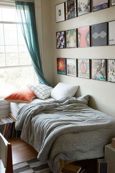 a bed sitting under a window next to a wall with pictures on the side of it