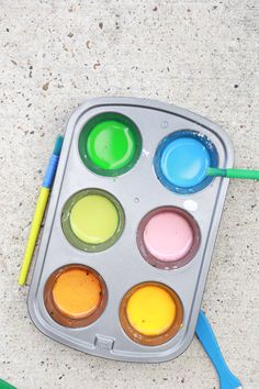 an empty tray with paint and a green brush on the floor next to some markers