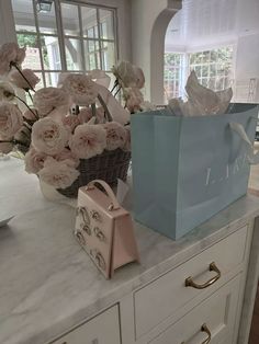 two bags sitting on top of a counter with flowers in the vases behind them