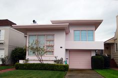 a pink house with two cars parked in front