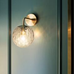 a wall light that is on the side of a blue door with a glass ball hanging from it