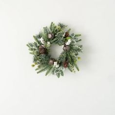 a christmas wreath with pine cones and silver baubles hanging on a white wall