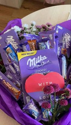 a bouquet of flowers and chocolates in a purple wrapper on top of a table