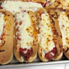 several hotdogs with cheese and sauce on them in a baking pan, ready to be eaten