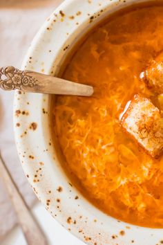 a white bowl filled with soup and tofu on top of a table next to utensils