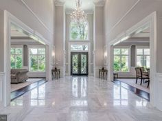 a large foyer with marble flooring and chandelier hanging from it's ceiling