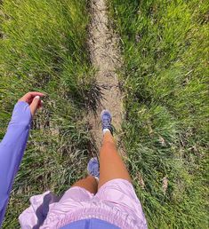 a person standing on top of a grass covered field next to a dirt road with their feet in the air