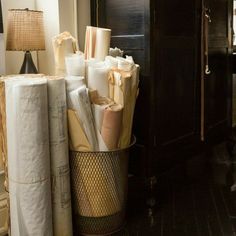 several rolls of toilet paper sitting in a trash can next to a lamp on a table