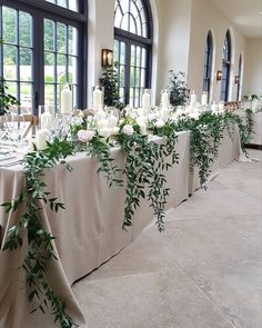 a long table is set up with candles and greenery for an elegant wedding reception