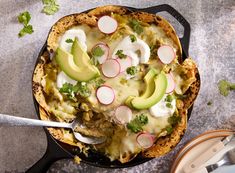 a skillet filled with food and topped with avocado, radishes and sour cream