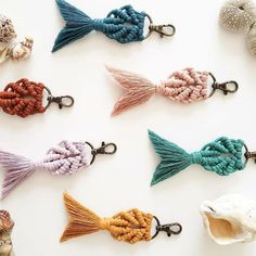 there are many different types of fish keychains on this white surface, one is multicolored and the other has tassels