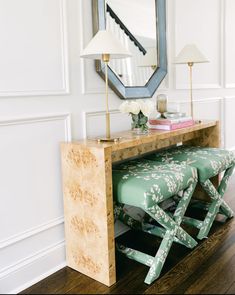 a table with a mirror, lamp and bench in front of it on top of a hard wood floor