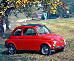 an old red car is parked in the grass