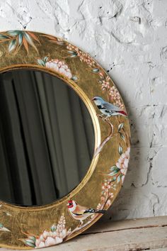 a mirror sitting on top of a wooden shelf next to a white painted brick wall