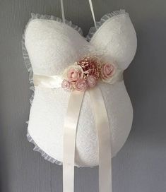 a white bra with pink flowers on it hanging from a hook in a room next to a wall