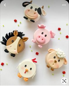 four farm animal cupcake toppers on a white table with sprinkles