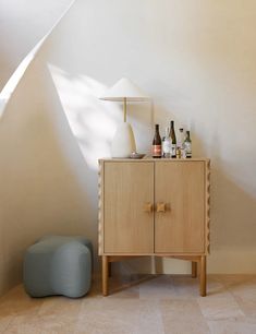 a wooden cabinet sitting next to a blue stool in a room with white walls and flooring