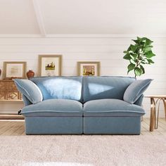 a blue couch sitting in a living room next to a wooden table and two pictures on the wall