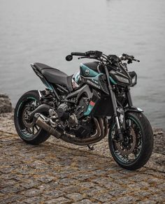 a black and blue motorcycle parked next to the water