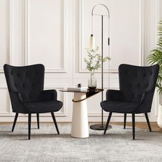 two black chairs sitting next to each other in front of a table with a potted plant