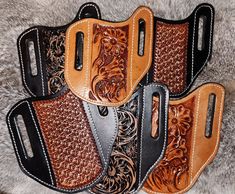 four leather holsters sitting on top of a furnishing area, each with an intricate design