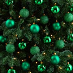 green ornaments are hanging from the top of a christmas tree