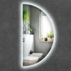 a white toilet sitting in a bathroom under a window next to a sink and potted plant