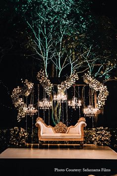 a couch sitting on top of a white table under a tree filled with lots of lights