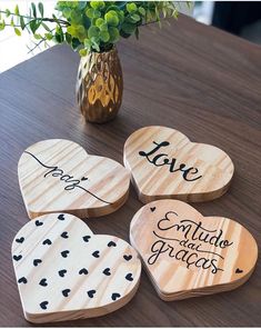 four wooden heart coasters sitting on top of a table next to a vase with flowers