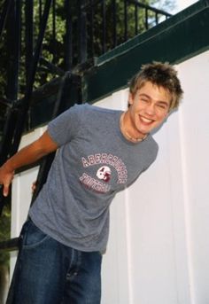 a young man is smiling while holding his skateboard