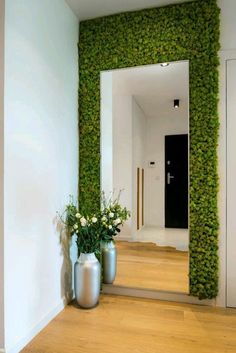 two vases filled with flowers sitting on top of a wooden floor next to a doorway